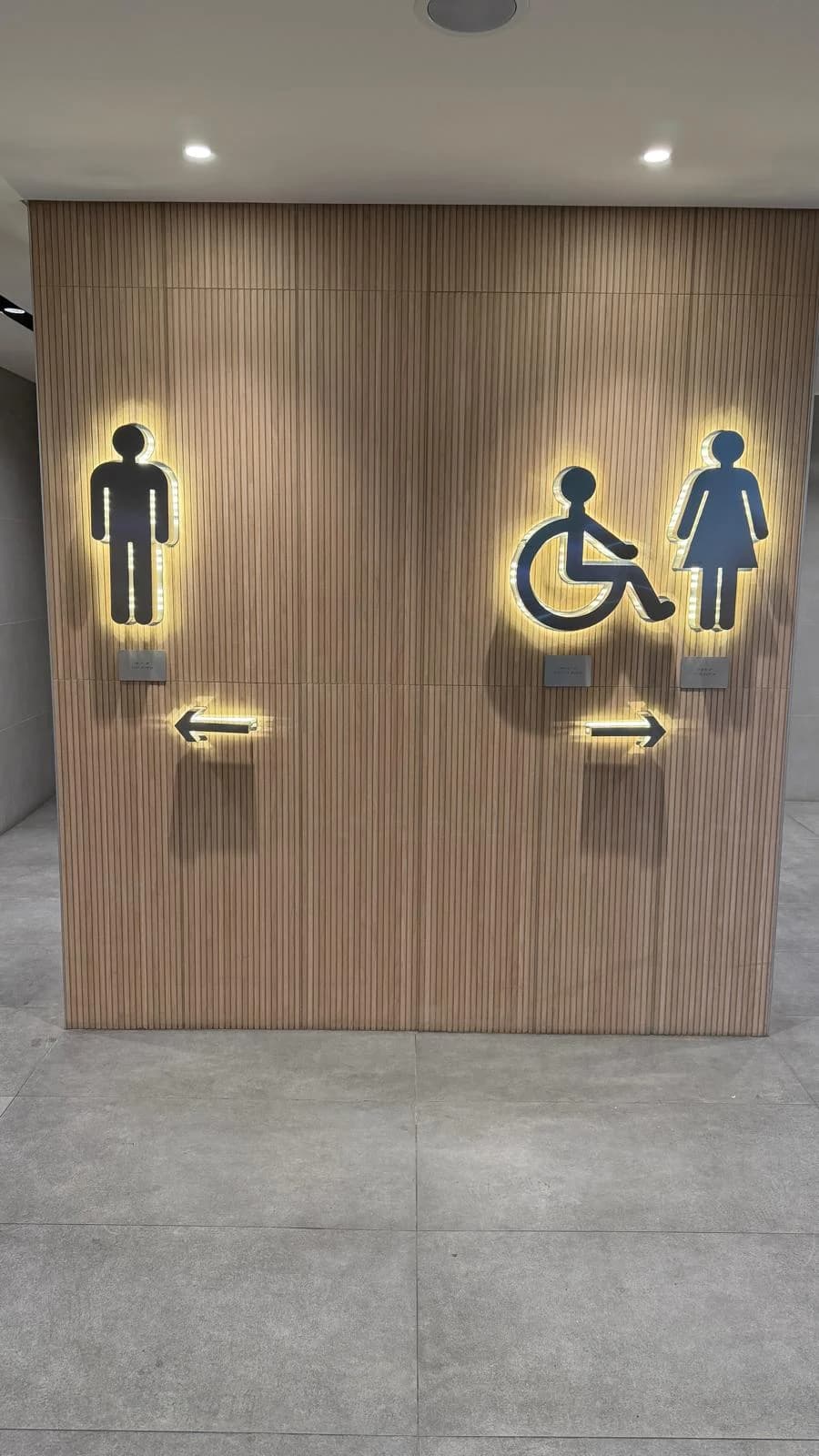 Ahşap lamel duvar üzerinde aydınlatmalı yönlendirme piktogramları
